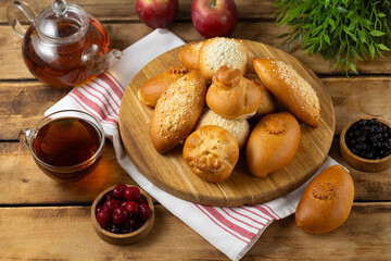 Wooden cutting board with assorted homemade tasty mini pie served with tea set on rustic background