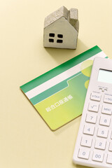 電卓と預金通帳とミニチュアの家