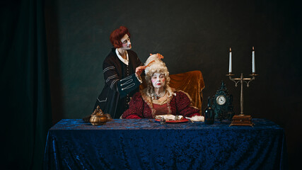 Obraz premium Loyal court favorite brushes wig of elegantly dressed empress, elderly woman in period attire, with serious face, sitting at table with serious face. Concept of history, comparison of eras