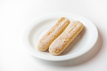 Italian savoiardi biscuits, ladyfinger cookies on white plate, isolated on white background