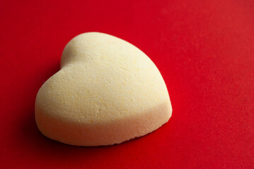 A white chocolate heart on a vibrant red background, symbolizing Valentine's Day love.