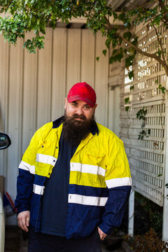 Aboriginal Australian man in workwear beside car after arriving home
