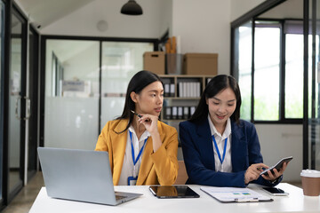 Young Asian woman discusses financial information with her business advisor before making an investment decision. and sign the document holding a pen Put your signature on official documents