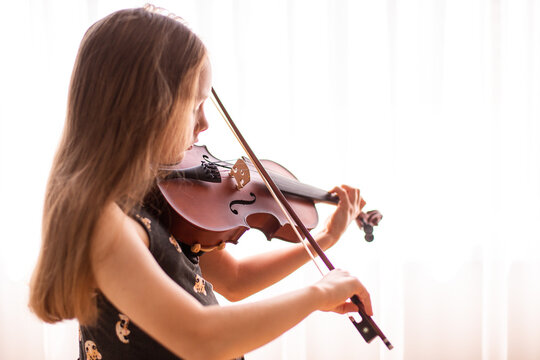ten year old girl practicing violin in front of a window