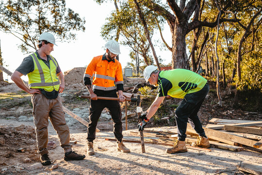 Construction workers driving a metal stake into the ground at construction site