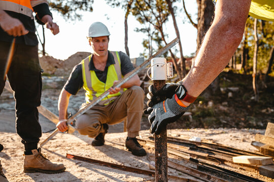 Construction workers driving a metal stake into the ground at construction site