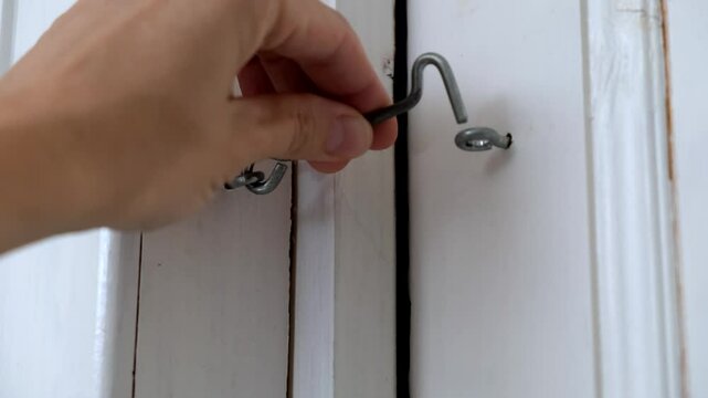 A person is currently opening a door with a hook in their hand
