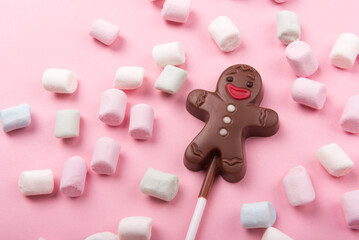 Chocolate man on pink background with marshmallows , sweet Christmas cookies, top view