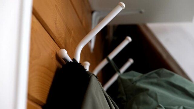 Hand hanging winter coat on hook in a corridor in autumn and winter, warm clothes for all the family