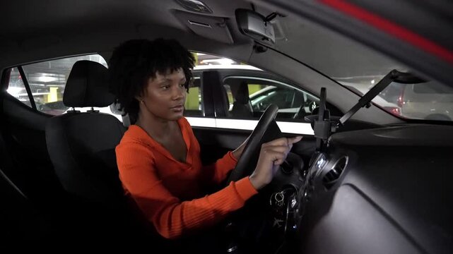 Young woman adjusting a gps navigation app while driving through a parking garage at night in an urban setting
