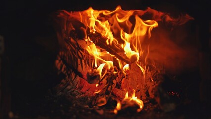 Cozy fireplace at night, burning wood logs glow warmly in shades of orange, red, and yellow,...