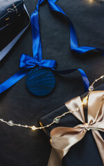 Blue Christmas tree ornament with satin bow, surrounded by gifts and garland, festive holiday decorations in elegant blue hue