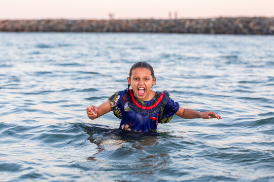 Torres Strait Islander child swimming in ocean water at dusk shouting loud