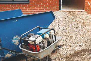 Construction site with wheelbarrow and portable petrol electricity generator 