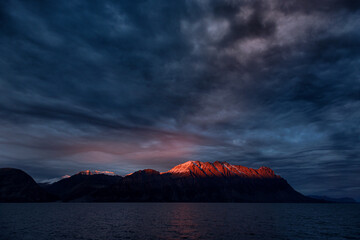 Setting sun glows red over the mountains of Antarctic Sound, King Christian X Land, Northeast Greenland National Park, at sunset. © Rixie