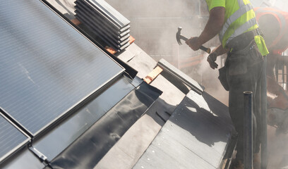Workers installing roof tiles around  solar panels on a residential roof during a bright day, showcasing the effort in renewable energy