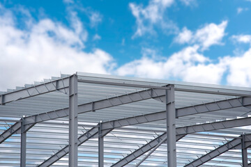 Fototapeta premium New construction project features steel framework under clear blue sky with scattered clouds in the afternoon