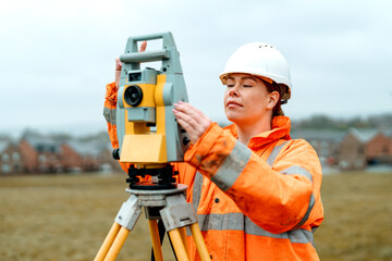 Female surveyor using precision equipment to measure land in cloudy weather during a construction project