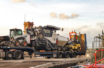 Construction vehicles loaded on a trailer at a construction site during the afternoon in an urban...