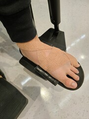 A close-up of a bandaged foot resting on a wheelchair footrest, symbolizing recovery and mobility challenges.