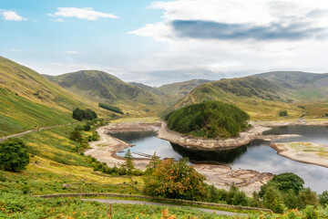 Naklejka premium Stunning landscape view of a serene lake surrounded by rolling hills in the countryside during a clear day