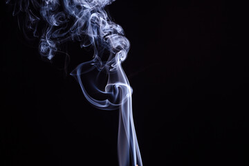 Wisps of smoke rising gracefully against a dark background in a calm and serene environment