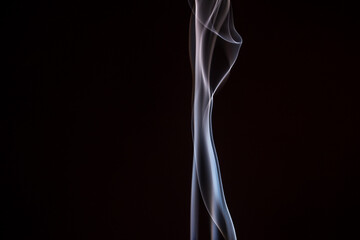 Ethereal wisps of smoke dancing gracefully against a dark backdrop in a tranquil moment of reflection and calmness