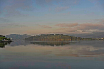 Tranquil Lake with Forested Island and Misty Hills