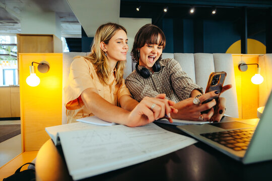Enthusiastic generation Z students taking a selfie in a library while collaborating on a project