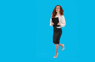 A businesswoman in a black pencil skirt and white blouse walks confidently holding a folder against a blue background