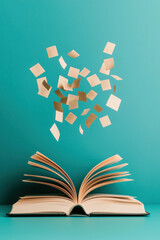 An open book with golden floating pages against a vibrant turquoise background, symbolizing creativity and inspiration in literature.