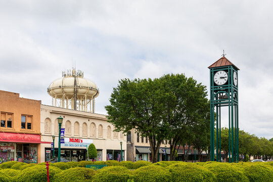 THOMASVILLE, NC, USA-8 MAY 2022: View of town clock, water tower and block of vintage store buildings across line of shrubbery.