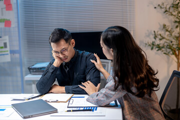 Businesswoman consoling upset businessman working late in office