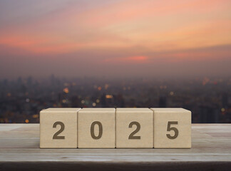 2025 letter on wood block cubes on wooden table over blur of cityscape on warm light sundown, Happy new year 2025 cover concept