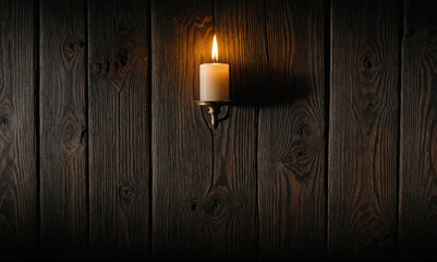 A single candle burns brightly on a wooden wall, casting a warm glow in the darkness