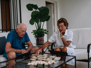 Marriage octogenarian play animatedly to a board game consisting of making combinations of numbers