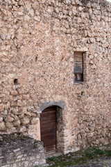 Rustic Stone Wall with Wooden Door and Window in an Old Spanish Building