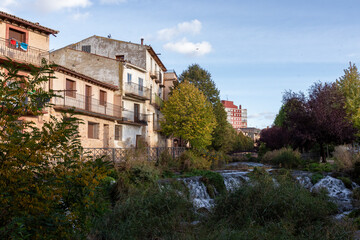 Fototapeta premium Charming Riverside Houses and Lush Vegetation Along a Small River in a Spanish Town