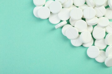 Pile of antibiotic pills on turquoise background, top view. Space for text