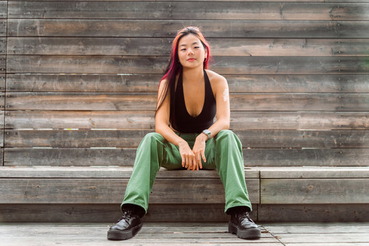 Asian woman sitting casually on wooden steps outdoors
