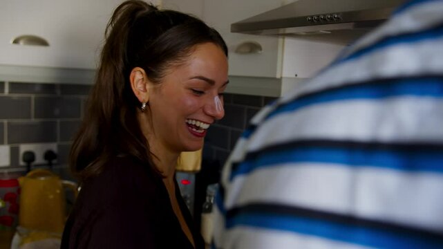 Cute young couple playfully cooking together and laughing boyfriend puts cream on girlfriends nose
