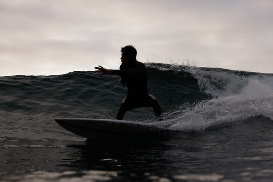 Surfer Riding a Powerful Wave at Dusk