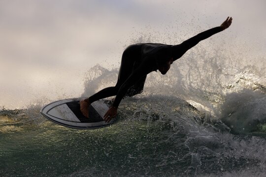 Surfer riding a wave against a dramatic sky backdrop