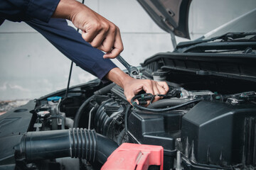 Mechanic using wrench while working on car engine outside the service center , Repair and service.