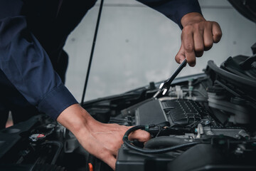 Mechanic using wrench while working on car engine outside the service center , Repair and service.