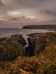 View between 2 mountain rocks over the Irish Sea and the Calf of Man from the sound. Dark moody skies and bright clouds.