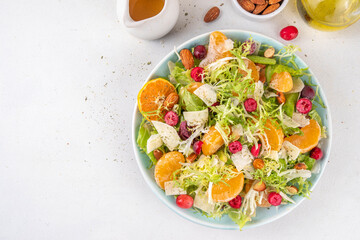 Salad bowl with lettuce, tangerines, nuts and cranberry
