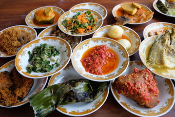 Assorted traditional Padang food is served in a plate on a table.