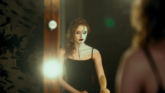Beautiful woman playing role of strong and independent person, doing art makeup . Split personality and duality, lady showing her real face and sexuality, medium portrait of actress in dressing room