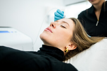 Side view of a young blonde girl undergoing carboxytherapy therapy to stimulate circulation in the...